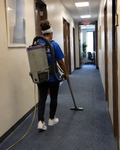 A OneCall crew member vacuuming a hallway with a backpack vacuum